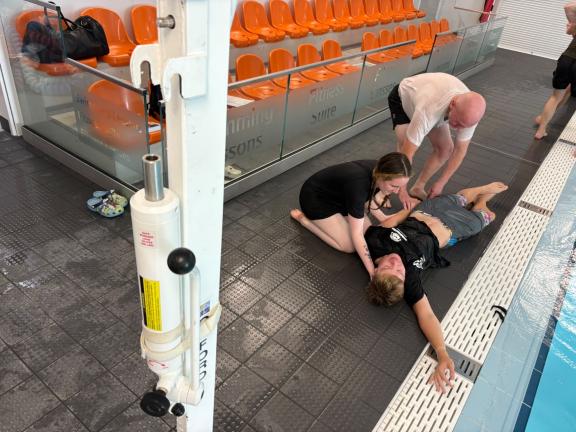 Person laying down receiving attention at side of pool