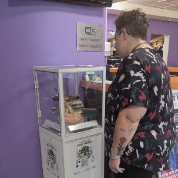 Lady looking at museum box with a barbie and typewriter